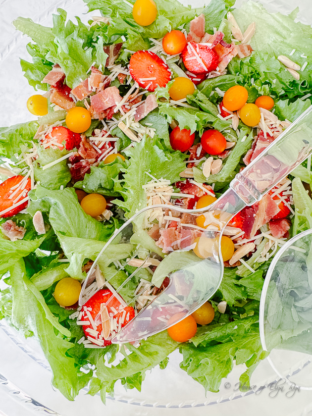 Salad greens with tomatoes and strawberries and a tangy dressing