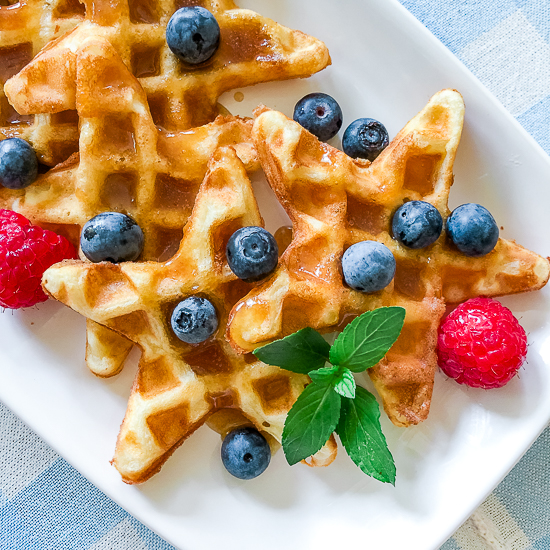 A platter with waffles in the shape of stars with fruit topping