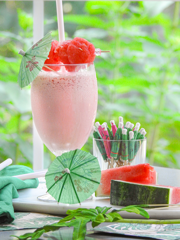 A watermelon shake in a goblet with watermelon pieces and umbrellas