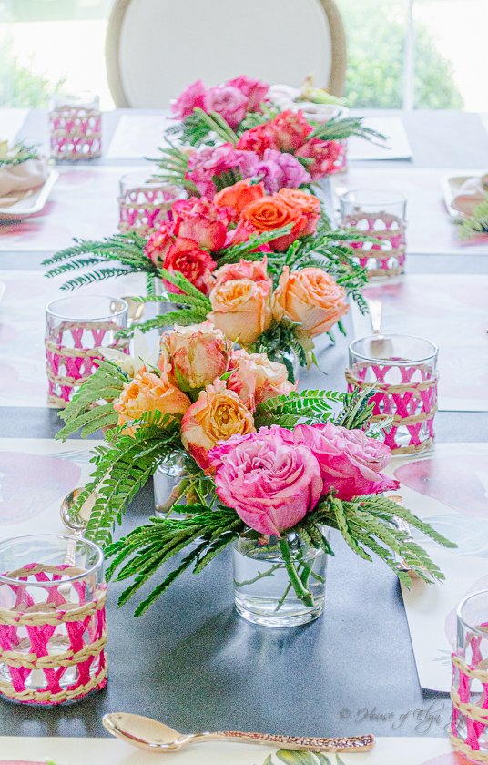 A tropical tablescape with small vases of vibrant roses