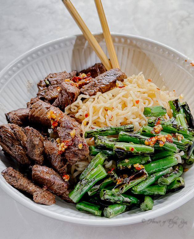 A bowl with beef, ramen noodles, and green beans