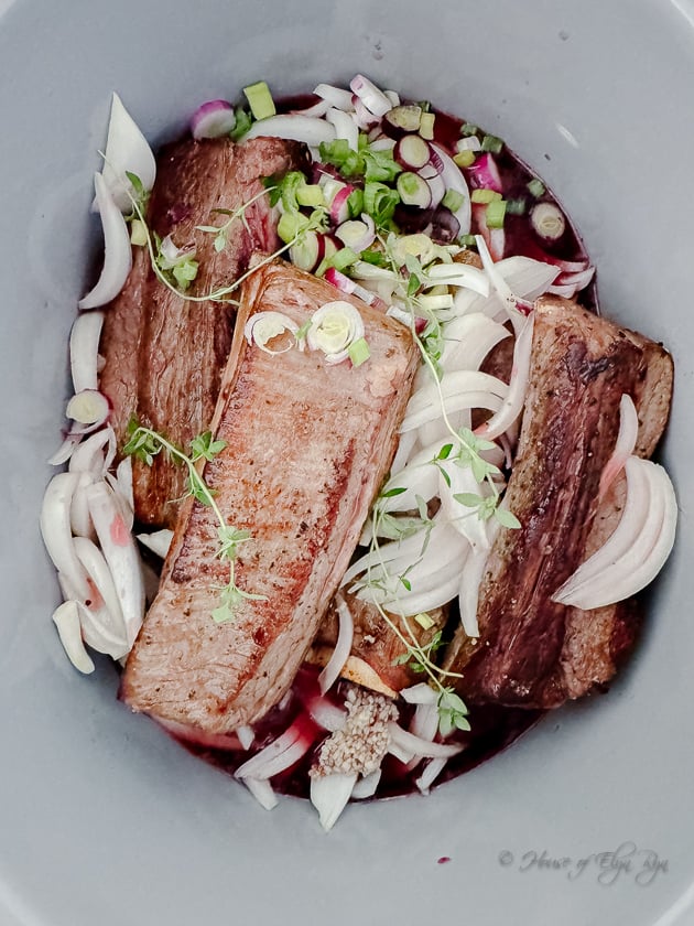 Adding garnish and red onions to the Pomegranate Short Ribs